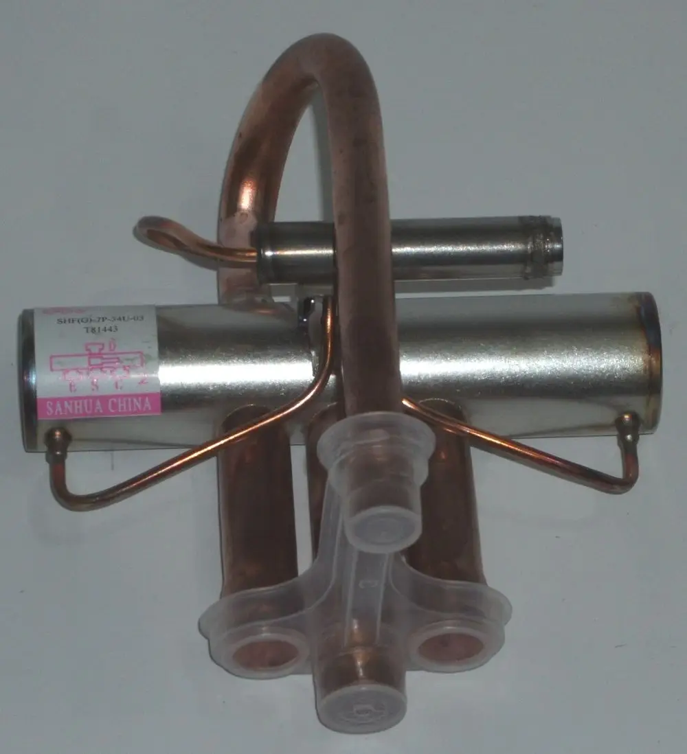 Kupfer- und Metallkomponenten eines Ventilkörpers, der Teil eines 4-Wege-Ventils von Daikin sein könnte, mit angeschlossenen Rohren und Verbindungselementen.